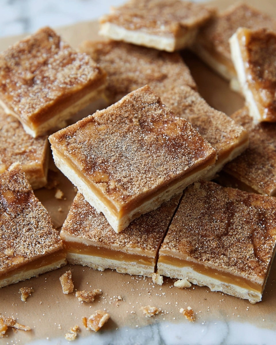 The image shows multiple square pieces of a layered snack lying close together on brown paper, placed over a white marbled surface. Each piece has two thin, light beige layers with a middle layer of gooey, golden caramel. The top layer is covered evenly with a mixture of cinnamon and sugar, giving it a grainy, brown speckled texture. Some pieces have small broken crumbs around them, showing the crisp edges and smooth caramel inside. photo taken with an iphone --ar 4:5 --v 7