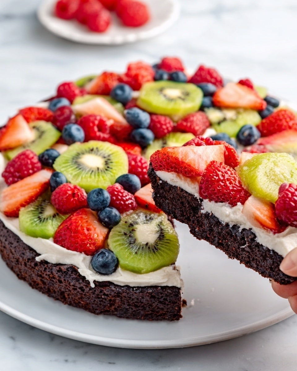 A round chocolate brownie cake is topped with a colorful mix of fresh fruit layers. The base is dark, dense, and moist chocolate brownie. On top, a layer of creamy white frosting spreads evenly, holding the fruit in place. The fruit layer includes bright red strawberries sliced into small pieces, vibrant green kiwi slices with visible seeds, plump red raspberries, and small, round blue blueberries scattered evenly. A woman's hand is lifting a slice, showing the thick brownie base beneath all the fresh fruit and frosting. The cake sits on a white plate against a white marbled background. Photo taken with an iphone --ar 4:5 --v 7