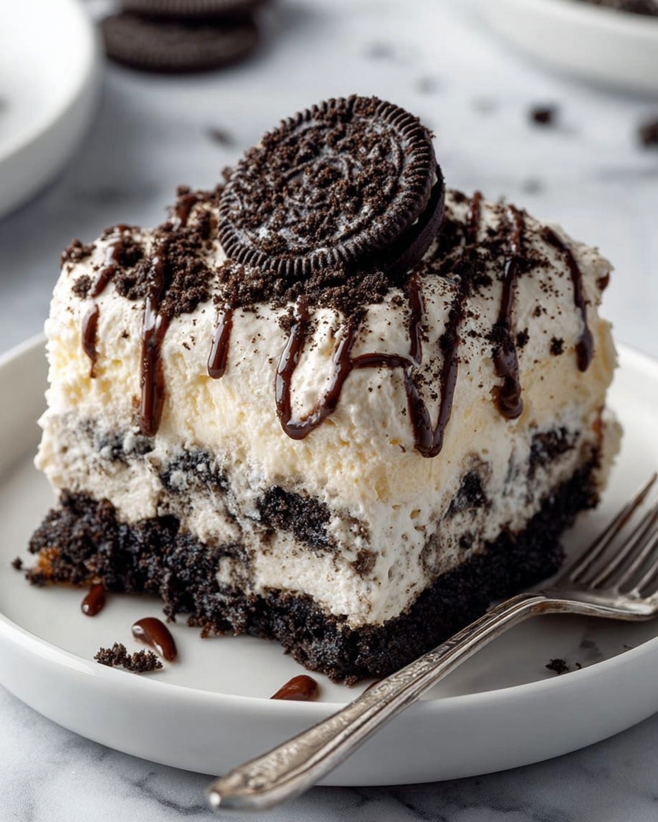 A square slice of layered Oreo dessert sits on a white plate with a silver fork on the side, resting on a white marbled surface. The dessert has at least three layers: a dark crushed Oreo crumb base, a thick creamy white middle layer dotted with Oreo pieces, and a top fluffy white layer sprinkled with Oreo crumbs. The top is decorated with a whole Oreo cookie and drizzles of dark chocolate sauce running down the sides. Photo taken with an iphone --ar 4:5 --v 7